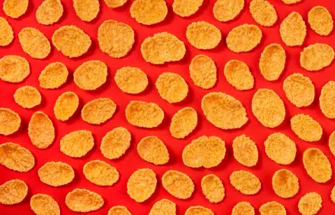 Pattern of corn flakes on red color background, top view Foto stock