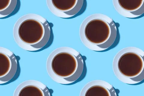 Pattern of cups of black coffee or tea on a blue background. Stock Photos