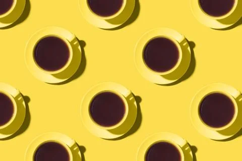 Pattern of cups of black coffee or tea on a yellow background. Stock Photos