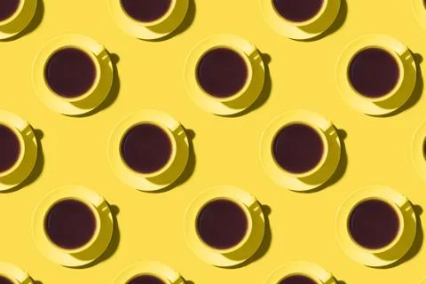 Pattern of cups of black coffee or tea on a yellow background. Stock Photos