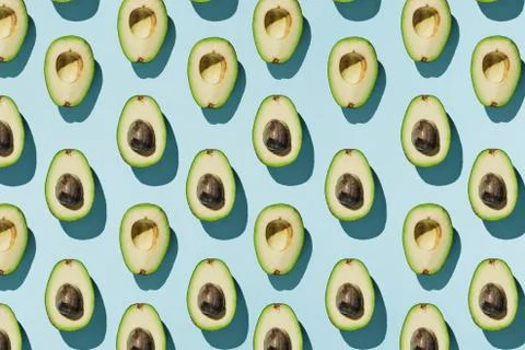 Pattern of cut avocado on blue background, healthy eating concept Stock Photos