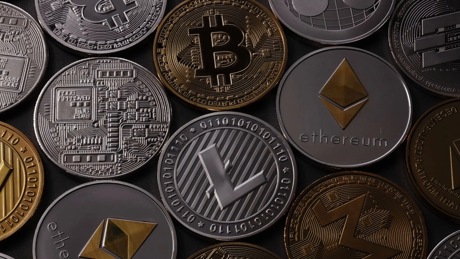 A pattern from different coins of crypto currency on a dark background. Slow