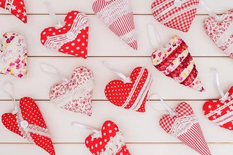 A pattern of different heart pads sewn by hand on a white wood background. Stock Photos