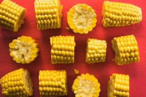 Pattern from different pieces of corn on a pink table Stock Photos