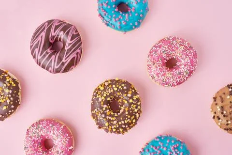 Pattern with different types of colorful donats decorated sprinkles and icing Stock Photos