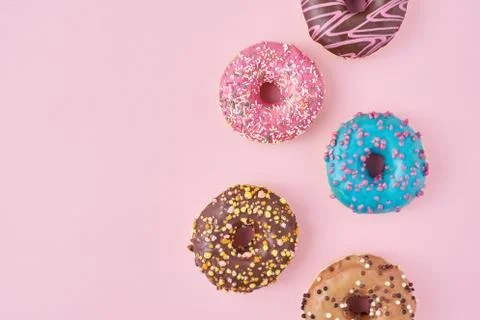 Pattern with different types of colorful donats decorated sprinkles and icing Stock Photos
