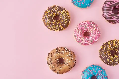 Pattern with different types of colorful donats decorated sprinkles and icing Stock Photos