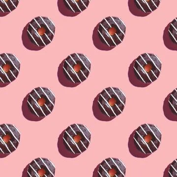 The pattern of a donut covered in chocolate with white stripes on a pink back Stock Photos