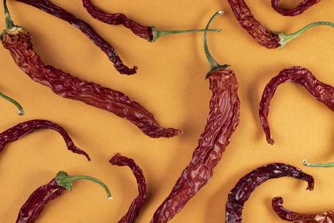 Pattern of dry red hot chili peppers on a orange background, top view, flat l Stockfoto's