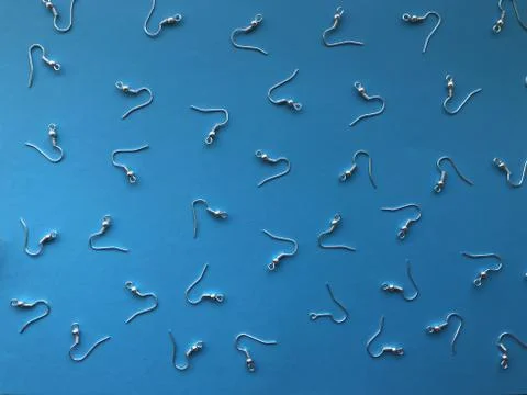 A pattern of earring hooks to create jewelry on a blue background. Basics for Stock Photos