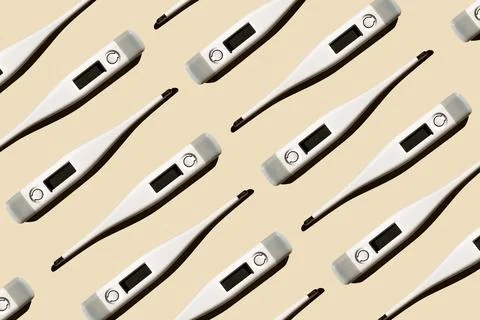 Pattern of electronic modern thermometers isolated on a pastel beige backgrou Stock Photos