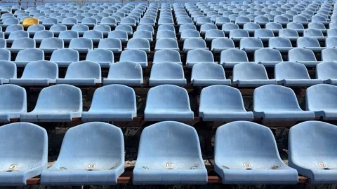 A pattern of empty blue stadium seats is broken by a single yellow seat Stock Footage 312400674