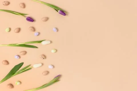 Pattern frame made of flowers and easter eggs on a beige background. 스톡 사진