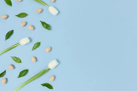 Pattern frame made of flowers and easter eggs on a blue pastel background. Stock Photos