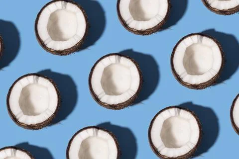 Pattern with Fresh coconut cut in half sliced on a pastel blue background Stock Photos