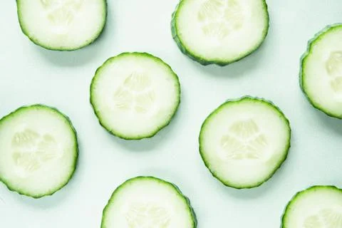 Pattern with freshly cut cucumber slices on green background Stock Photos