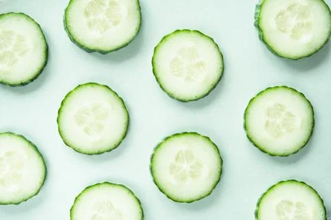 Pattern with freshly cut cucumber slices on green background Stock Photos