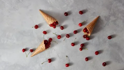 Pattern of freshly picked ripe cherries in a sweet wafer cones on a gray Foto stock