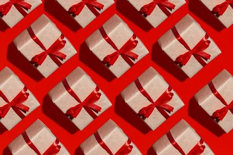 Pattern gift box in kraft paper with red ribbon bow insulated on red. Stock Photos