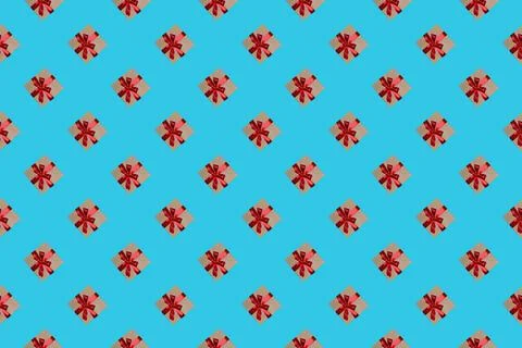 A pattern of gift boxes with a bow made with ribbon isolated on a light blue  Foto stock