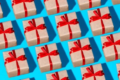 Pattern gift square box in paper with red ribbon bow insulated on blue. Stock Photos