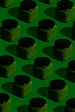 Pattern of glass jars of eatable adjika green sauce. Pop-art style. Stock Photos