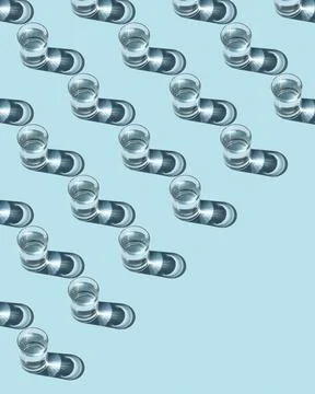Pattern from glasses with water on a blue background. Ecological concept. Stock Photos