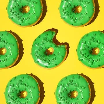 Pattern of green donuts on a yellow background. Square, studio photo. Stock Photos