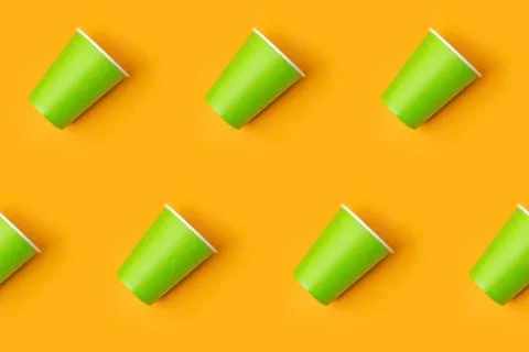 Pattern from green paper drinking cups arranged diagonally on yellow backgrou Foto stock