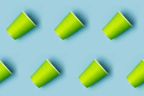Pattern from green paper drinking cups arranged diagonally on blue background Foto stock