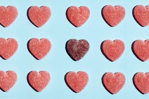 Pattern of gummy vitamin candy in shape of heart on blue background. Concept. Stock Photos
