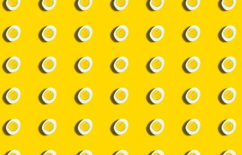 A pattern with a half of a boiled egg cut off on a yellow background. Grocery Stock Photos