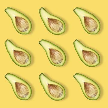 Pattern of halved avocado with bone on a yellow background. 스톡 사진