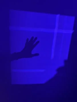 Pattern of indigo blue light with hand casting a hard shadow Foto stock