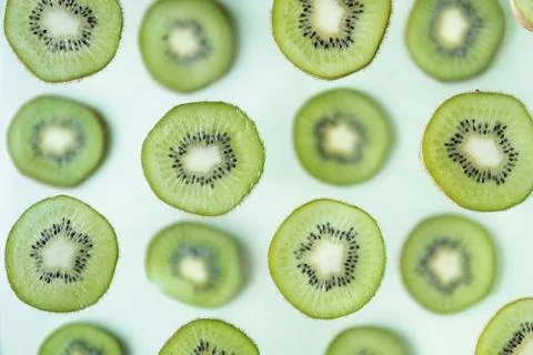 Pattern of kiwi slices levitating above green background Stock Photos