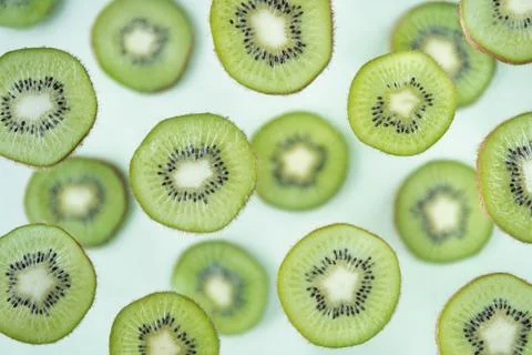 Pattern of kiwi slices levitating above green background Stock Photos