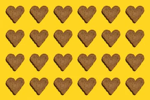 Pattern made with bread in heart form on yellow background, as backdrop or te Foto stock