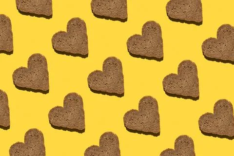 Pattern made with bread in heart form on yellow background, as backdrop or te Foto stock