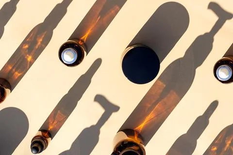 Pattern made with brown glass bottle of cosmetic products and strong shadow o Stock Photos