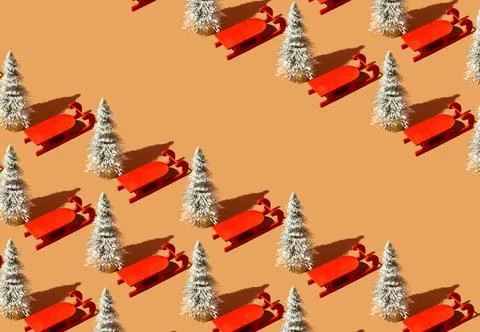 Pattern made with Christmas tree and red sleigh against pastel orange backg.. Stock Photos