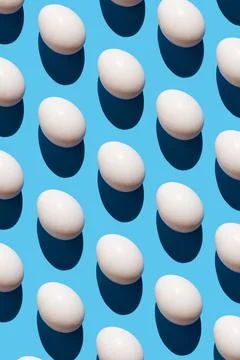 Pattern made of eggs on pastel blue background. Minimal food concept. Stock Photos