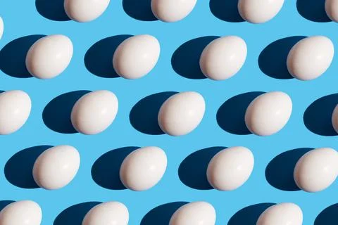 Pattern made of eggs on pastel blue background. Minimal food concept. Stock Photos