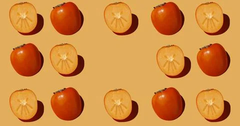 Pattern is made with half a persimmon on a beige background. Stock Photos