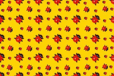 Pattern made with ladybugs on yellow background, as backdrop or texture. Brig Stock Photos