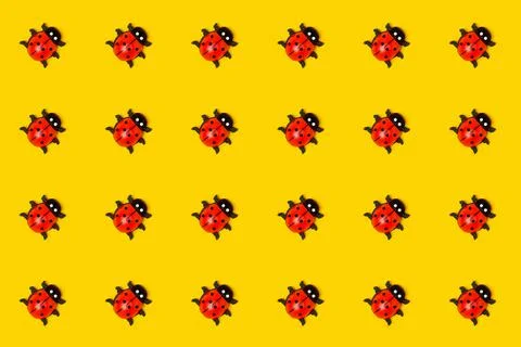 Pattern made with ladybugs on yellow background, as backdrop or texture. Brig Stock Photos
