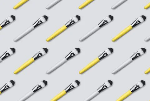 Pattern made from make up brushes on gray background. Stock Photos