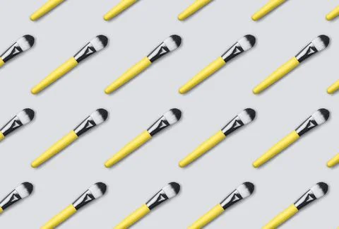 Pattern made from make up brushes on gray background. Stock Photos