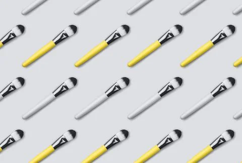 Pattern made from make up brushes on gray background. Stock Photos