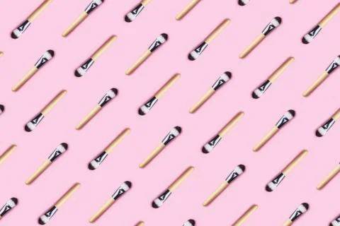 Pattern made from make up brushes on pink background. Stock Photos