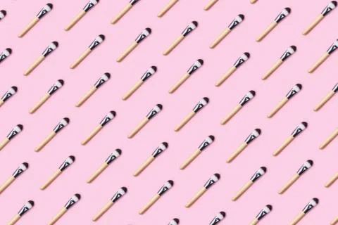 Pattern made from make up brushes on pink background. Stock Photos